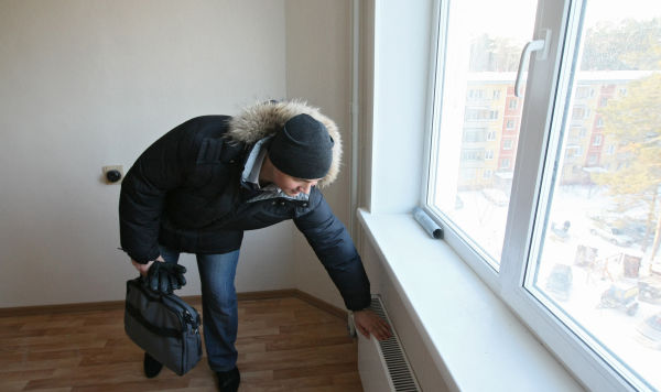Мужчина поверяет температуру батареи Мужчина поверяет температуру батареи