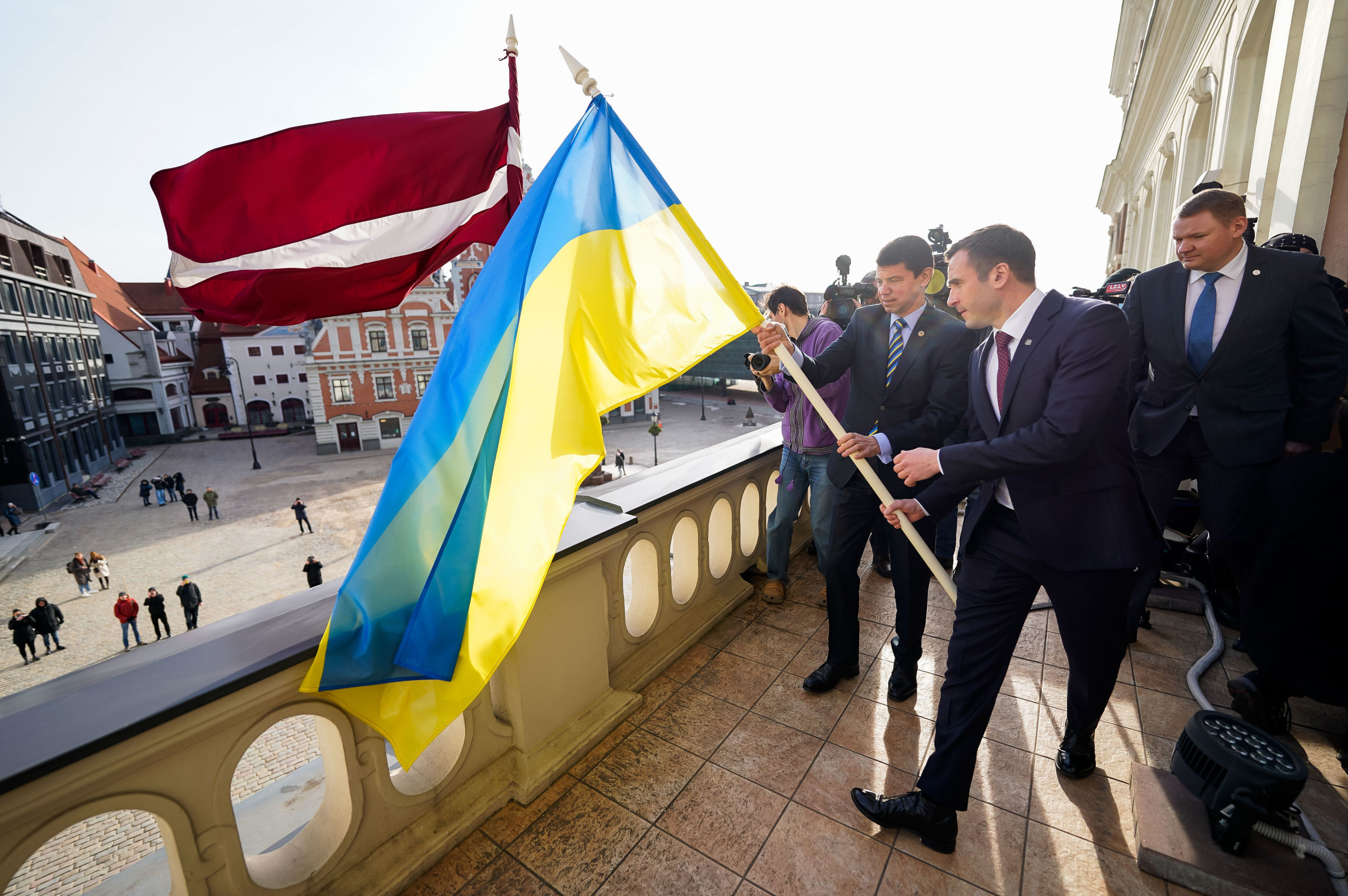 Мэр Риги Мартиньш Стакис, вице-мэр Эдвардс Смилтенс и посол Украины Александр Мищенко водружают флаги флаг Украины на здание Рижской думы