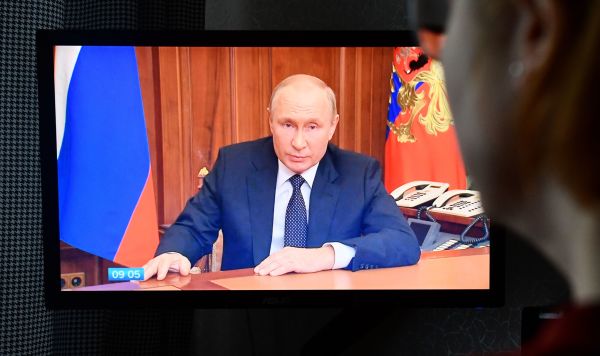 Женщина смотрит трансляцию срочного телеобращения президента РФ Владимира Путина к гражданам России, 21 сентября 2022