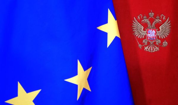 Флаг Евросоюза на фоне стены с гербом РФ