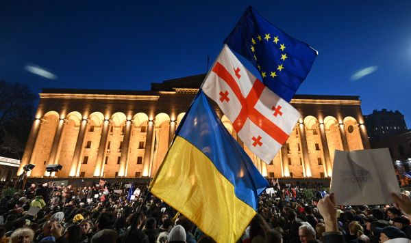 Протестующие размахивают грузинским, украинским и европейским флагами во время демонстрации у здания парламента Грузии в Тбилиси, 8 марта 2023 года