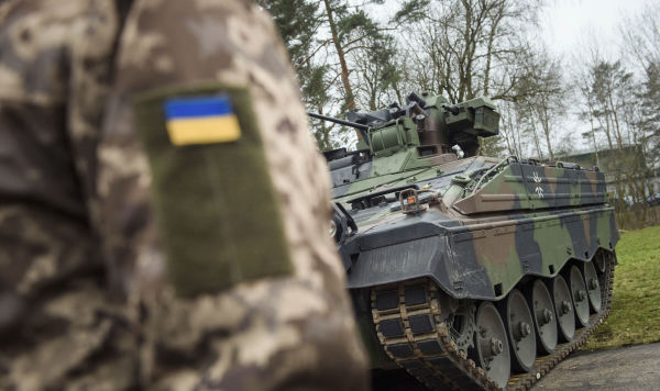 Украинский солдат стоит перед БМП Украинский солдат стоит перед БМП
