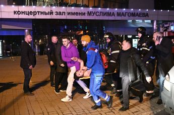 Раненую женщину несут к машине скорой помощи во время теракта в "Крокус Сити Холле", 22 марта 2024