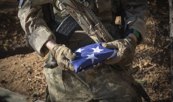 Американский наемник - боец ВСУ держит в руках флаг США Американский наемник - боец ВСУ держит в руках флаг США