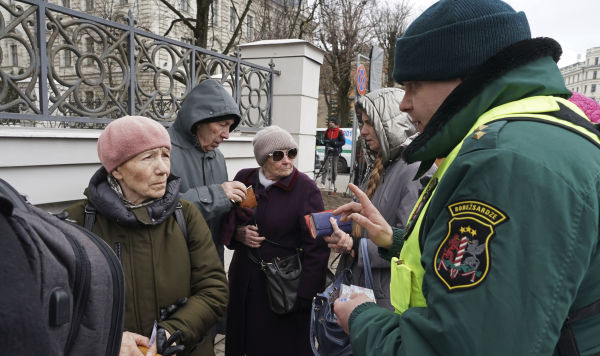 Латвийский пограничник проверяет документы у граждан России Латвийский пограничник проверяет документы у граждан России, проживающих в Латвии, которые пришли на избирательные участки в посольстве России для участия в президентских выборах в Риге, Латвия, воскресенье, 17 марта 2024 года.
