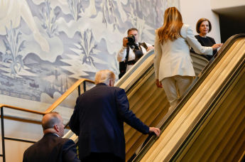 Президент Дональд Трамп (в центре) и первая леди Мелания Трамп (справа вверху) поднимаются по эскалатору в штаб-квартире ООН во вторник, 23 сентября 2025 г.