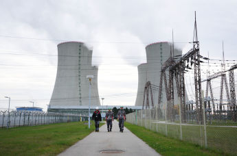 Рабочие проходят мимо градирен атомной электростанции Дукованы, Чехия, 21 октября 2025 года