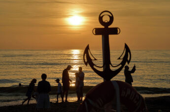 Российские отдыхающие наблюдают закат на берегу моря в Янтарном