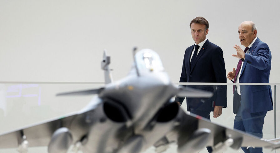 Президент Франции Эммануэль Макрон (слева) рассматривает макет истребителя Rafale.