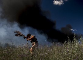 Местная жительница у легкового автомобиля на трассе Луганск-Краснодон, загоревшегося в результате попадания снаряда.