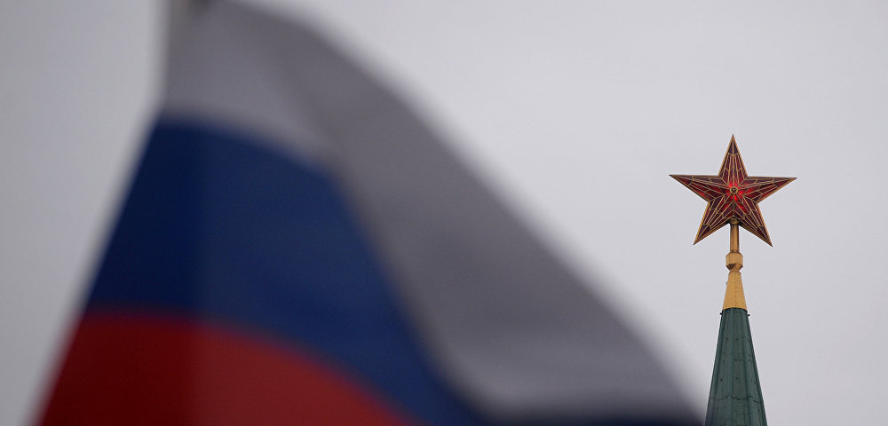 Шпиль одной из башен Московского Кремля и государственный флаг России на Красной площади Шпиль одной из башен Московского Кремля и государственный флаг России на Красной площади