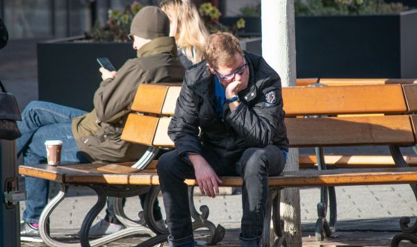Молодой человек сидит на скамейке Молодой человек сидит на скамейке