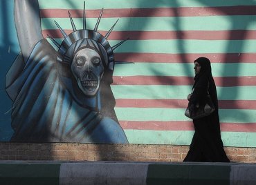 Женщина идет вдоль стены здания бывшего посольства США в Тегеране.